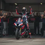 A Trackhouse Aprilia rider celebrates a strong result with his team in the pit garage.