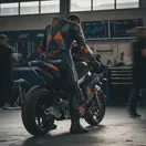A MotoGP rider contemplates his helmet and bike in the pit garage before a session.